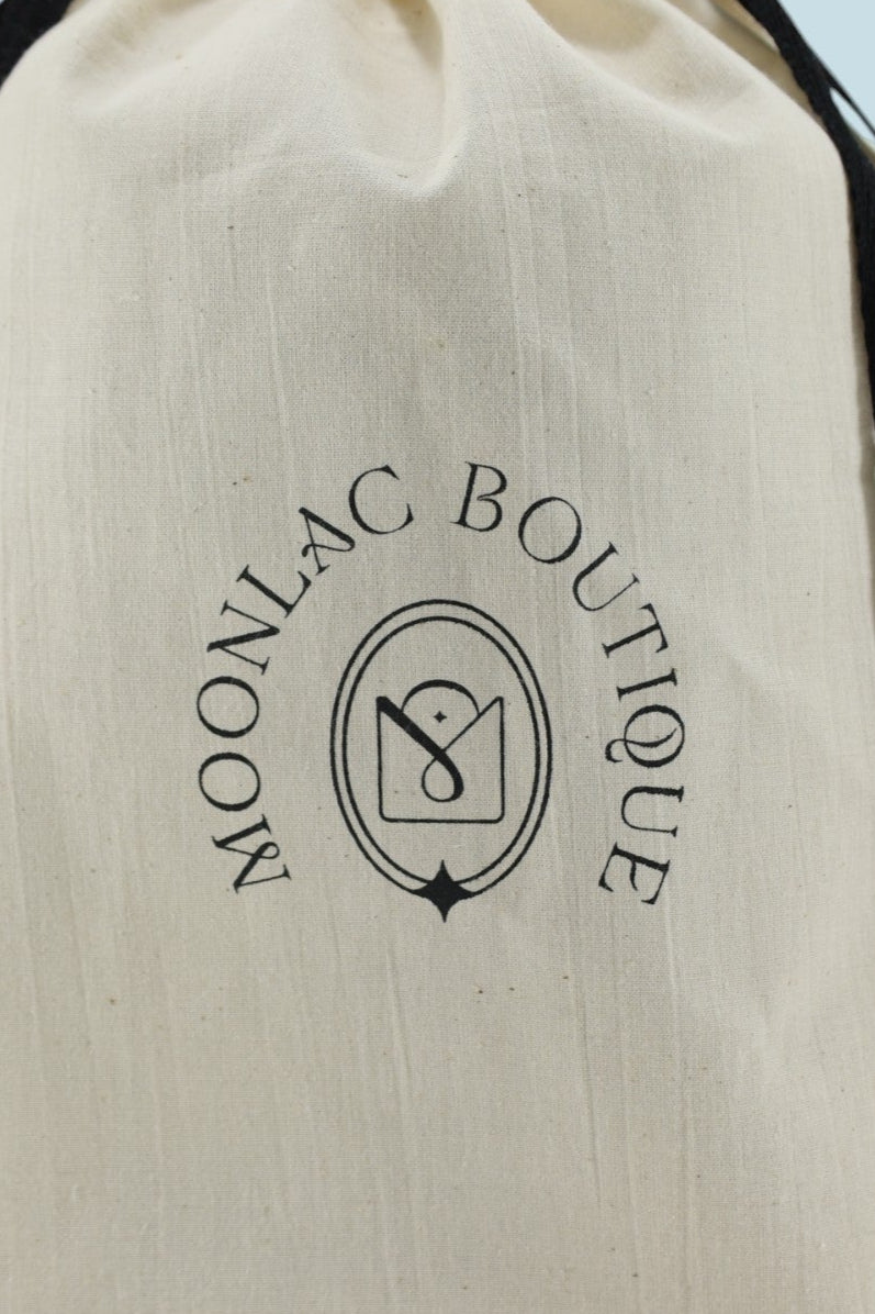 Pochon Moonlac en coton Écru pour ranger tous vos accessoires, debout avec le logo "Boutique Moonlac"