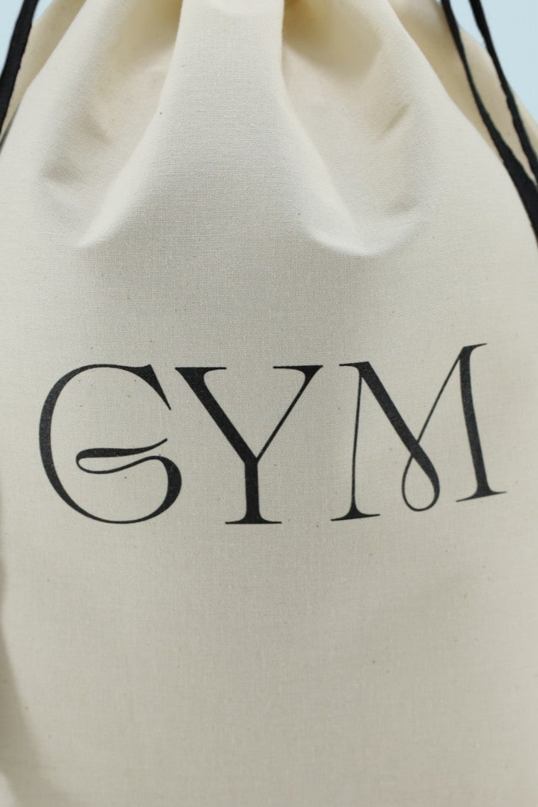 Sac Moonlac en coton écru avec inscription noire GYM, cordons noirs, posé debout